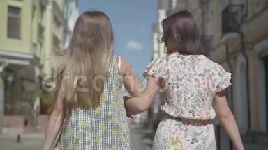 两个带购物袋的步行妇女的后景。 年轻女孩穿着时髦的夏装，享受着<strong>花钱</strong>